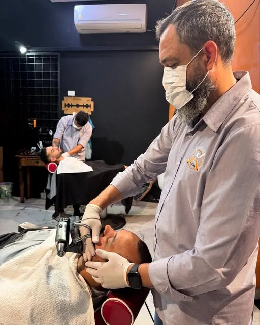 Barbeiro da Tegon fazendo a barba de um cliente no salão