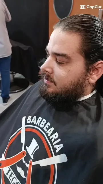 Cliente de barba cheia e cabelo longo na cadeira